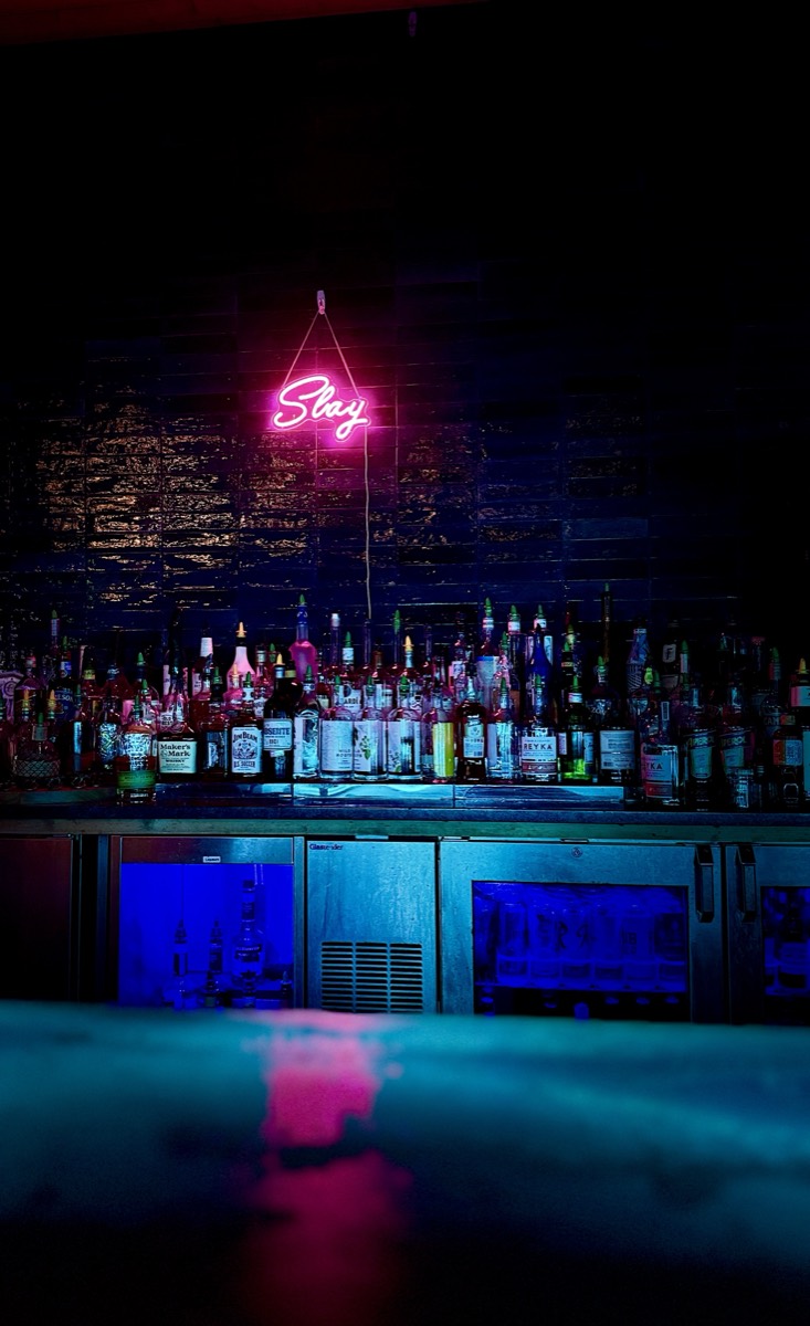 Back bar glowing pink and blue under the Slay neon